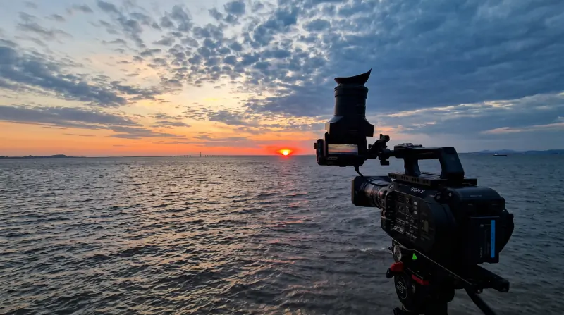 Broadcast camera filming a sunset over the water